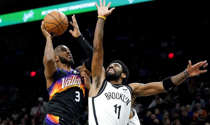 Chris Paul de Phoenix Suns busca anotar ante la marca de Kyrie Irving